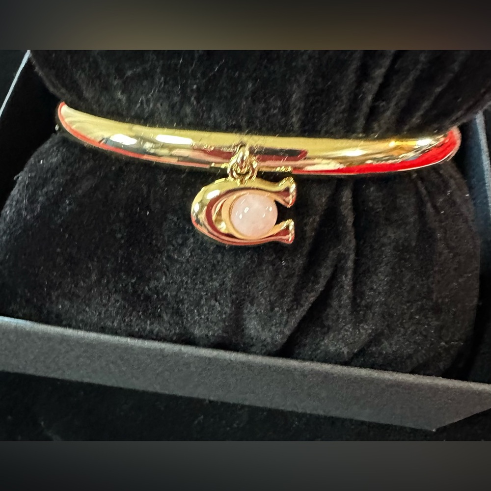 Coach bangle with C initial holding a pink stone